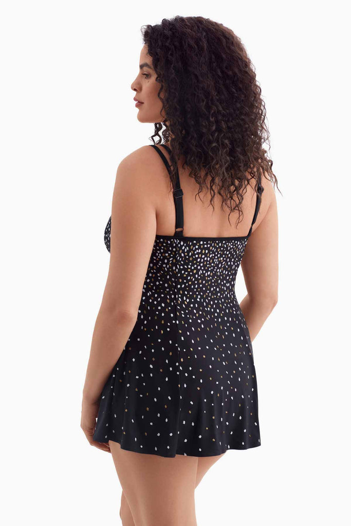 Woman turned left wearing a black swim dress with multicolored dots