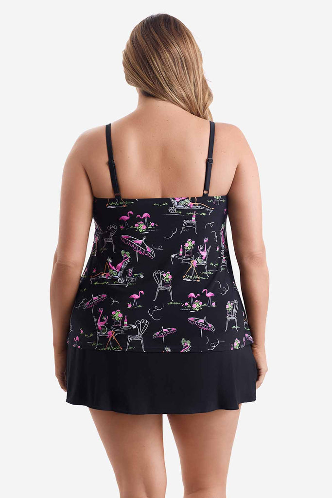 Woman turned away wearing a black tiered one-piece swimsuit with a flamingo print