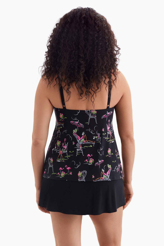 Woman turned away wearing a black tiered swim dress with a flamingo pattern