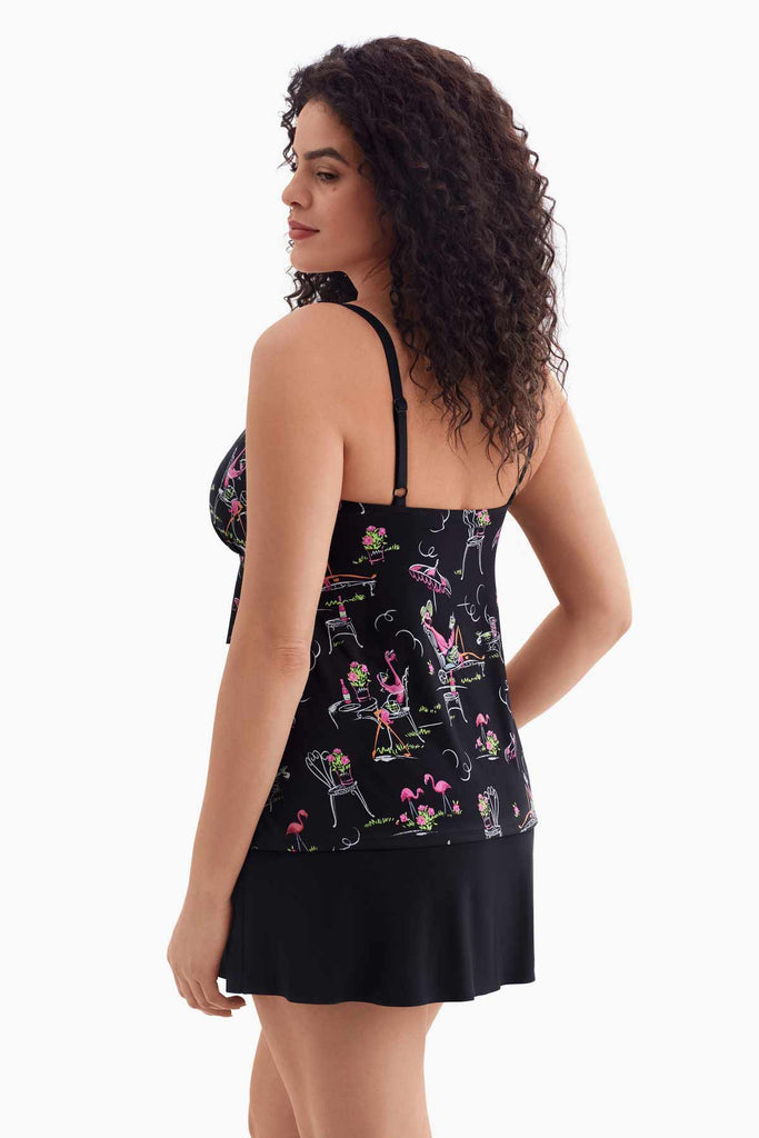 Woman turned left wearing a black tiered swim dress with a flamingo pattern