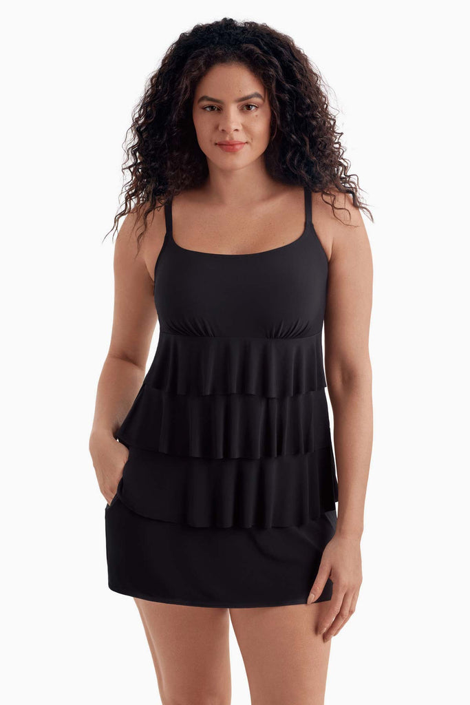 Woman wearing a black tiered swim dress with her hand in pocket