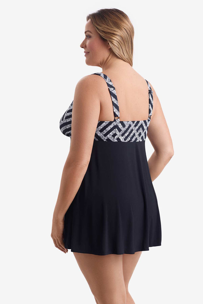 Woman turned left wearing a one-piece swim dress with a black and white pattern on the bust