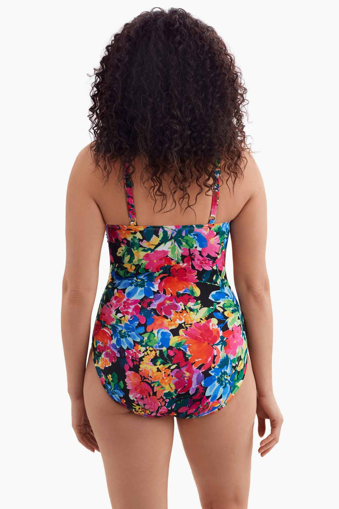 Woman faced away wearing a one-piece swimsuit with a multicolored floral print