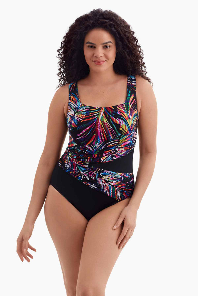 Woman wearing a wrap-sash one-piece swimsuit with a multicolored pattern