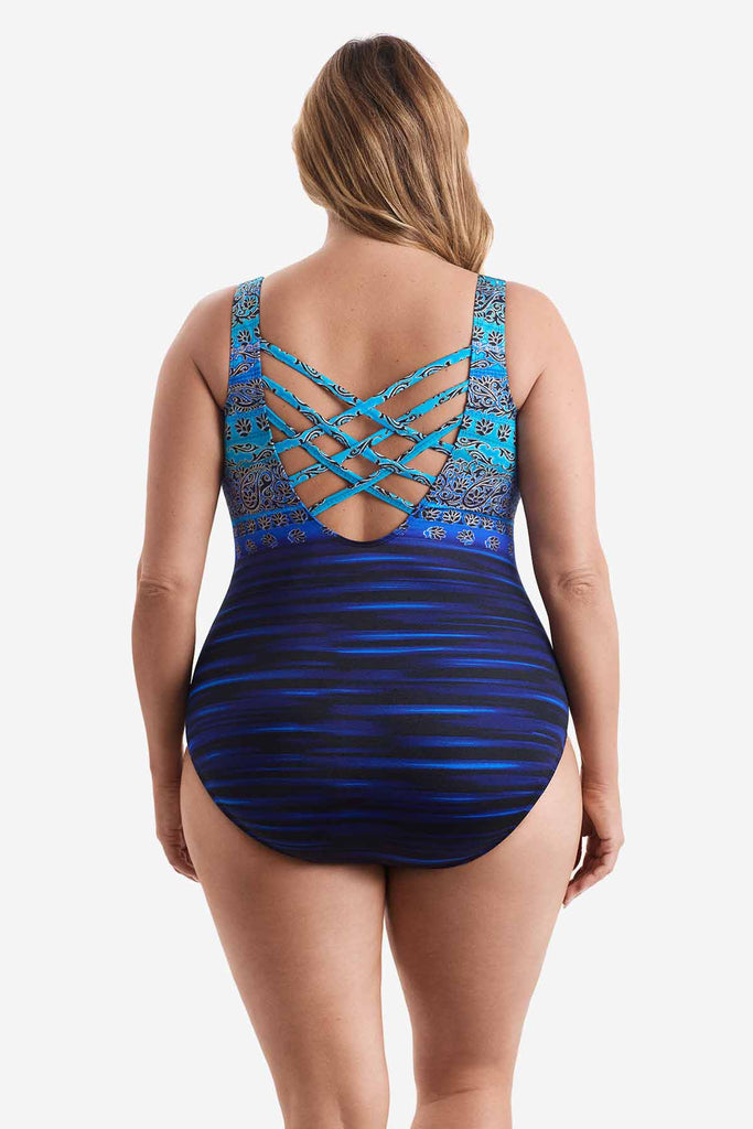 Woman turned away wearing a one-piece swimsuit with various blue patterns throughout suit