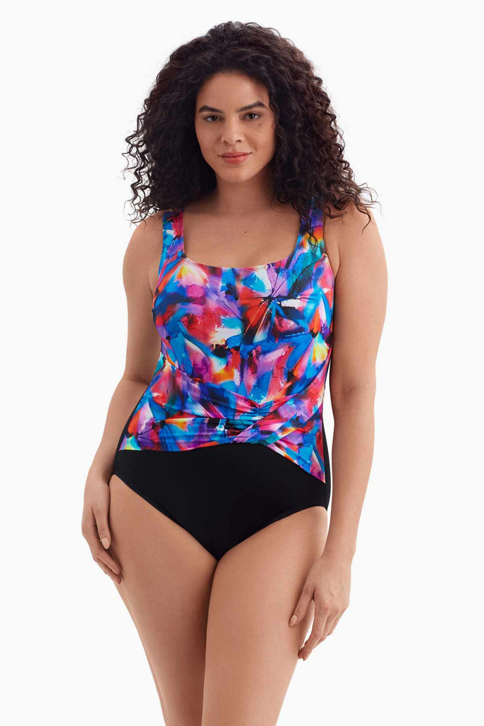 Woman wearing a one-piece swimsuit with a multicolored watercolor pattern