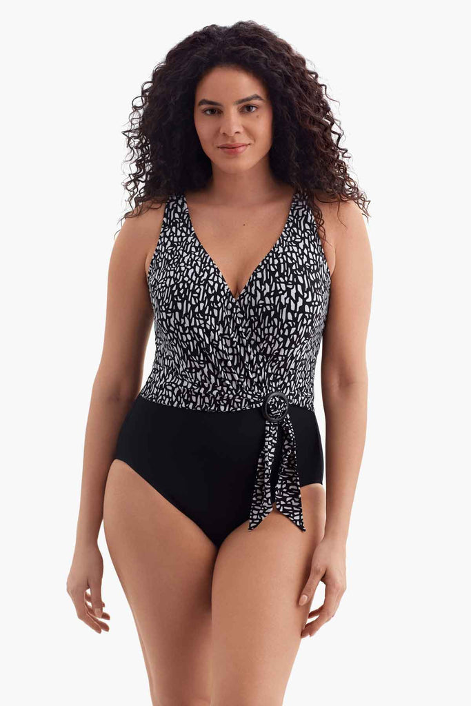 Woman wearing a one-piece black and shite swimsuit with a side tie detail