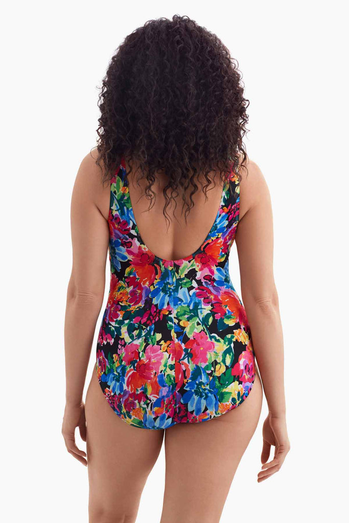 Woman turned away wearing a multicolored floral one-piece swimsuit 