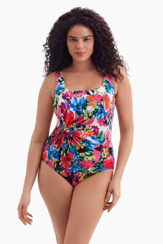 Woman wearing a multicolored floral one-piece swimsuit with a twist drape on the side