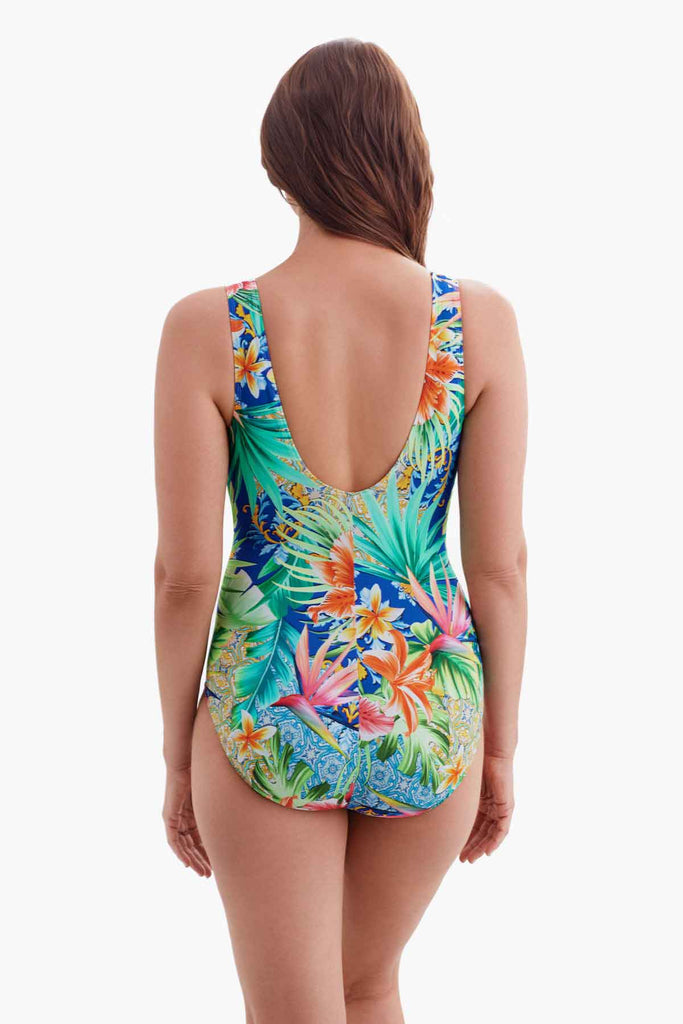 Woman faced away wearing a one-piece swimsuit with a multicolored palm leaf pattern