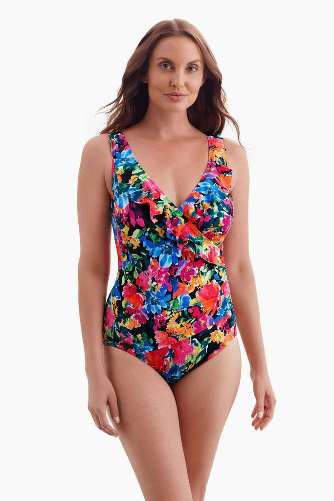 Woman wearing a multicolored floral patterned one-piece swimsuit with a ruffle down the neckline 