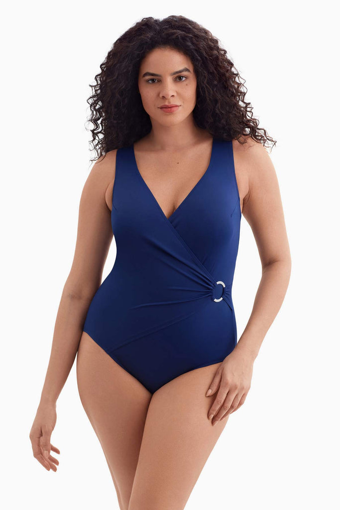 Woman wearing a navy blue one-piece swimsuit with an O ring on the side