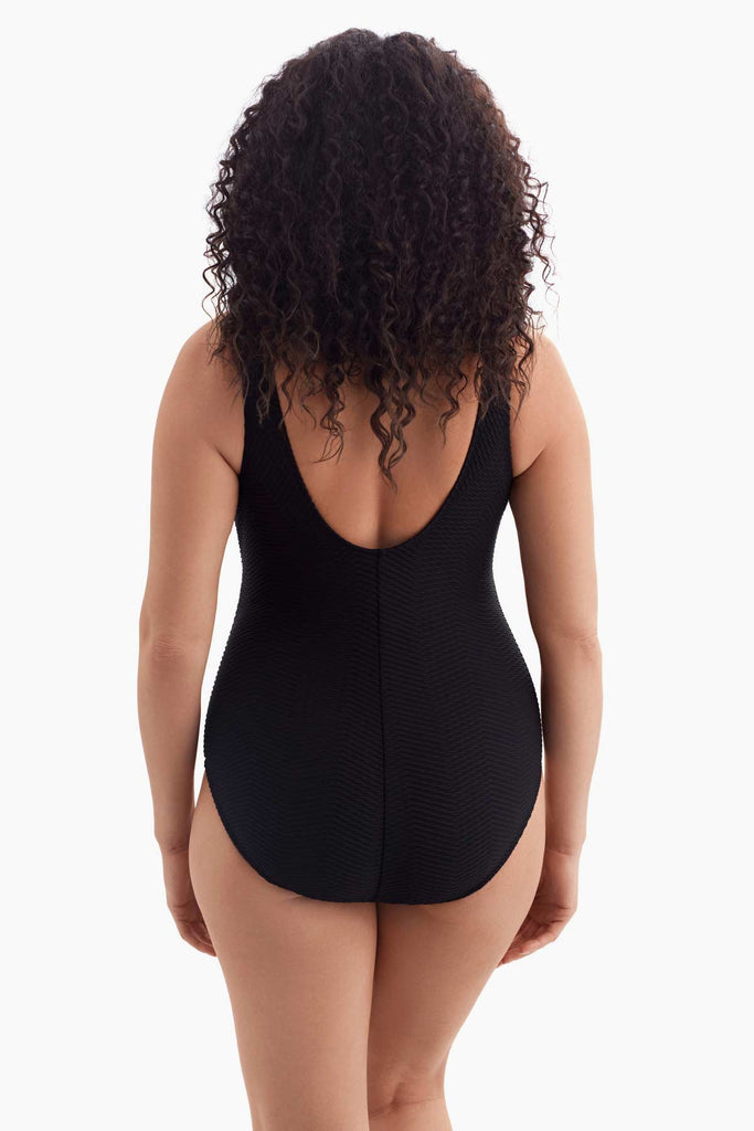 Woman turned away wearing a black and white one-piece swimsuit 