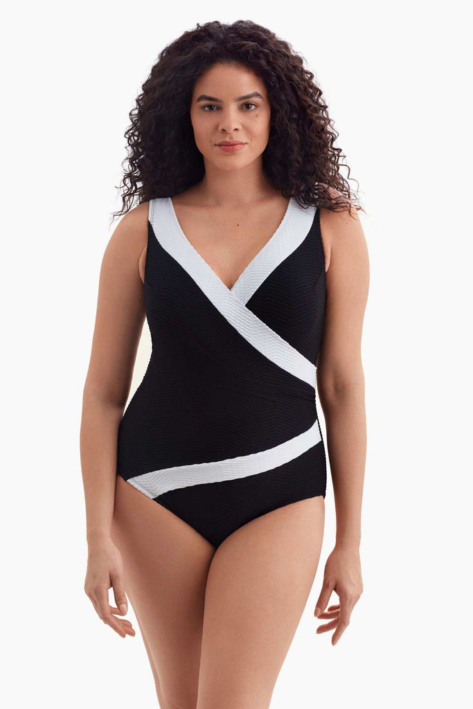 Woman wearing a one-piece swimsuit with a white trim along the neckline