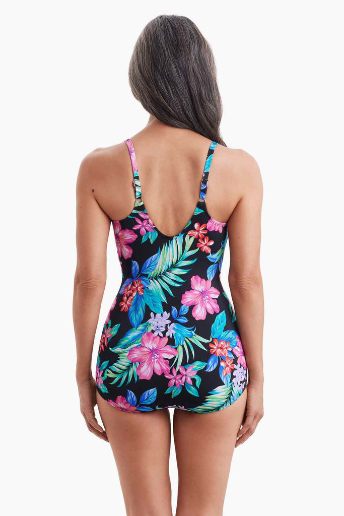 Woman facing away wearing a one-piece swimsuit with a multicolored floral print