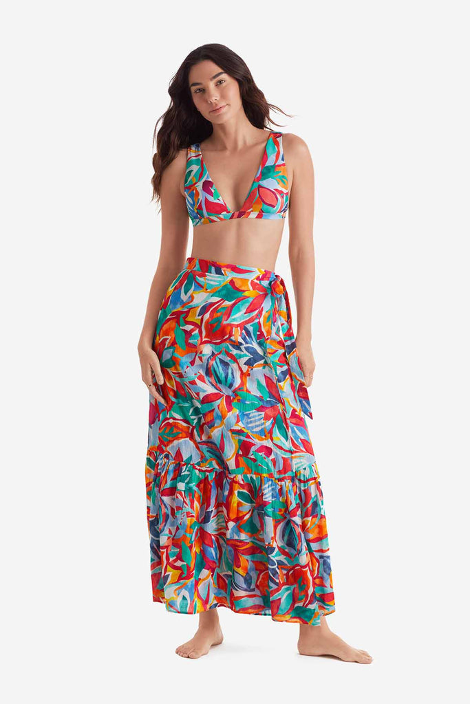 Woman wearing a multicolored bikini top with a multicolored floral wrap skirt