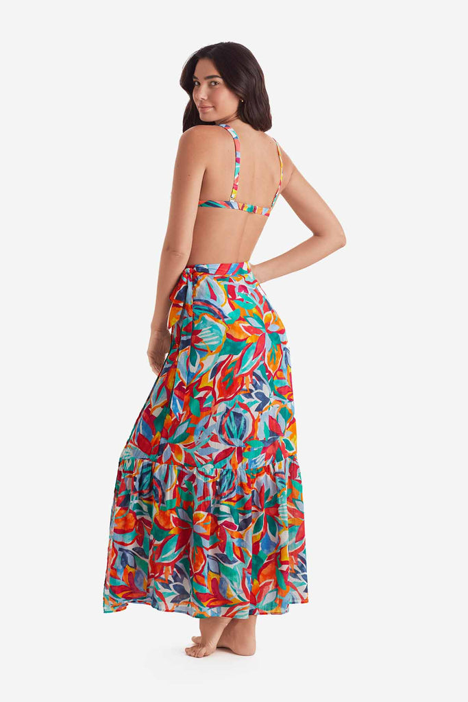 Woman turned left wearing a multicolored bikini top with a multicolored floral wrap skirt