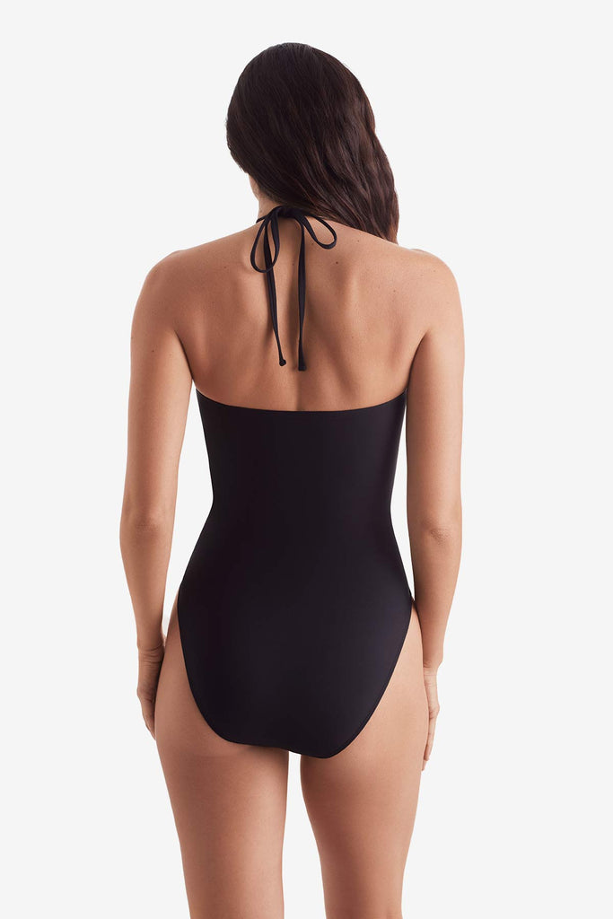 Woman turned away wearing a black one-piece swimsuit 