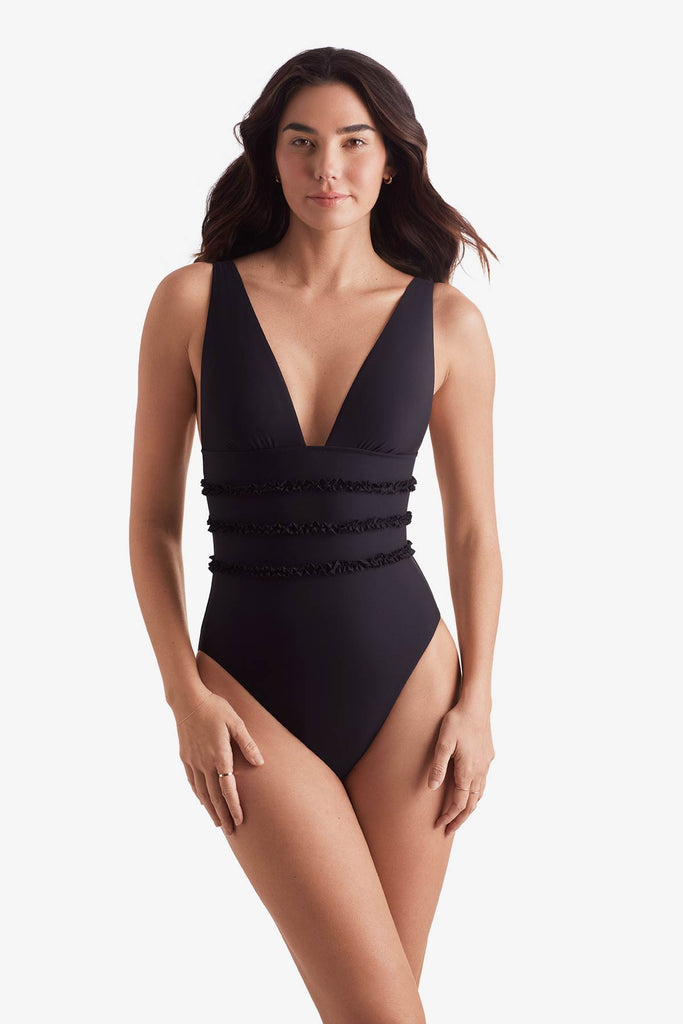 Woman wearing a black one-piece swimsuit with ruffles on the waist