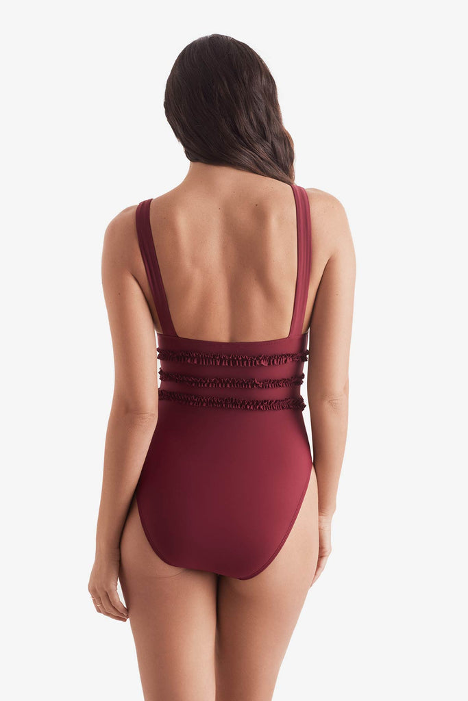 Women turned away wearing a dark red one-piece swimsuit with ruffles on the waist