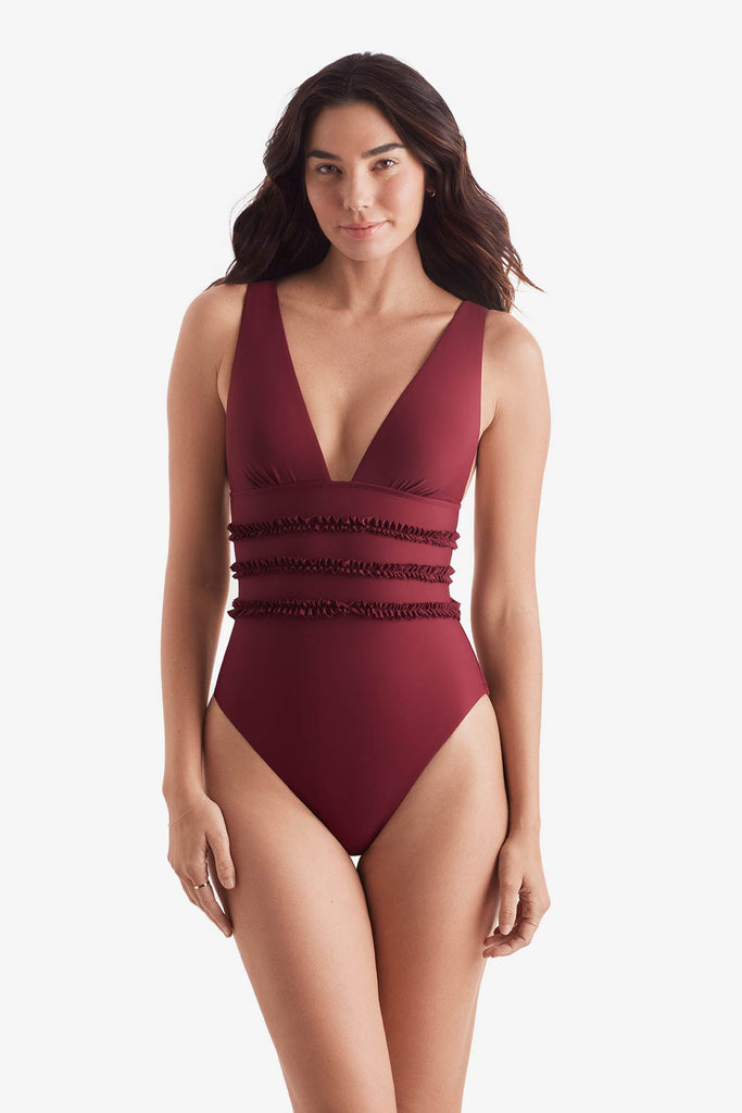 Women wearing a dark red one-piece swimsuit with ruffles on the waist