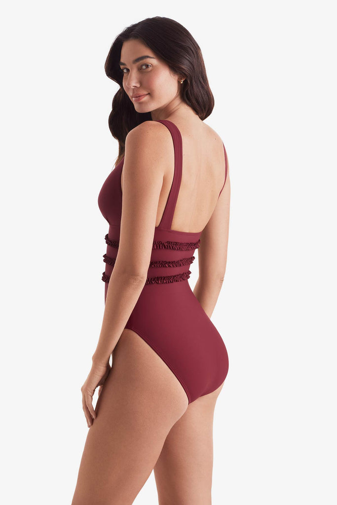 Women turned left wearing a dark red one-piece swimsuit with ruffles on the waist