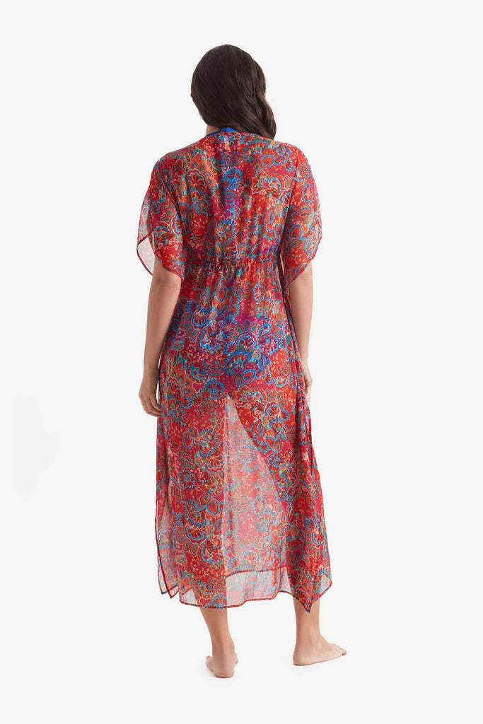 Woman turned away wearing a sheer multicolor paisley print caftan swim cover up