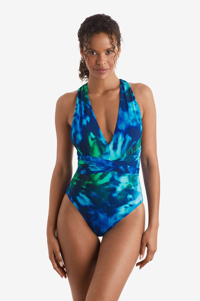 Woman wearing a blue and green tie dye one-piece swimsuit with a deep V neckline