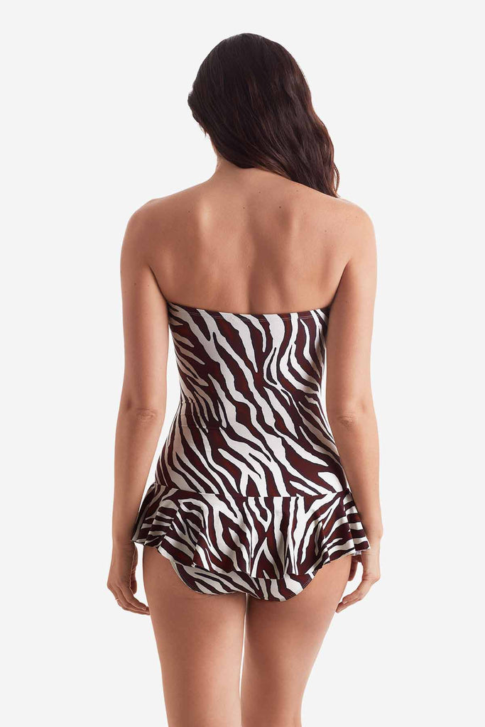 Woman turned away wearing a zebra print one piece swimsuit with skirted leg