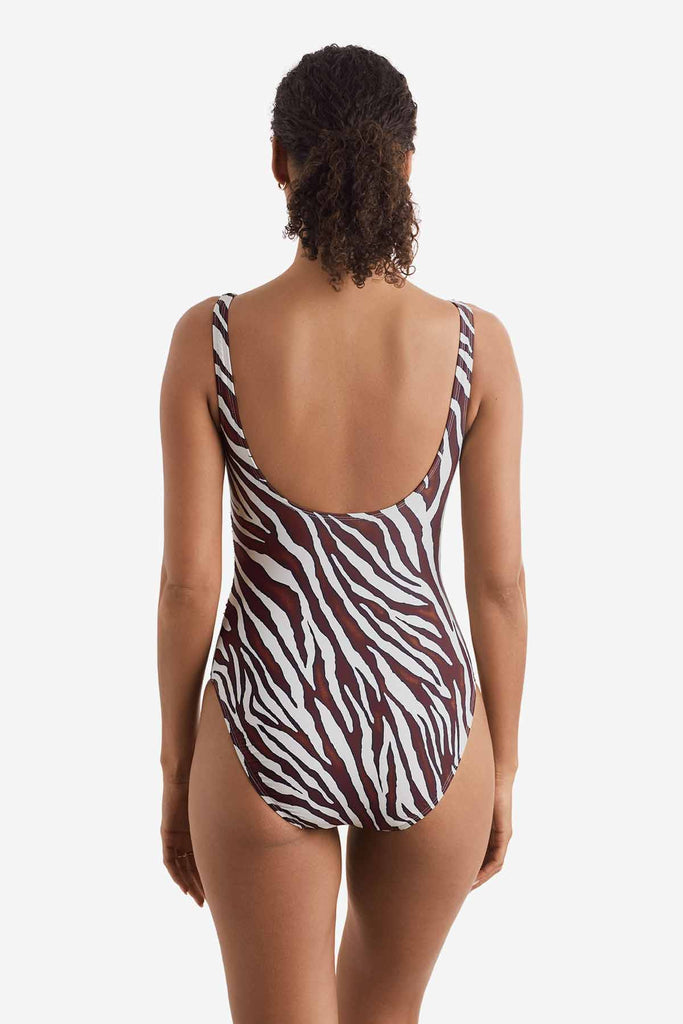 Woman turned away wearing a one-piece zebra print swimsuit